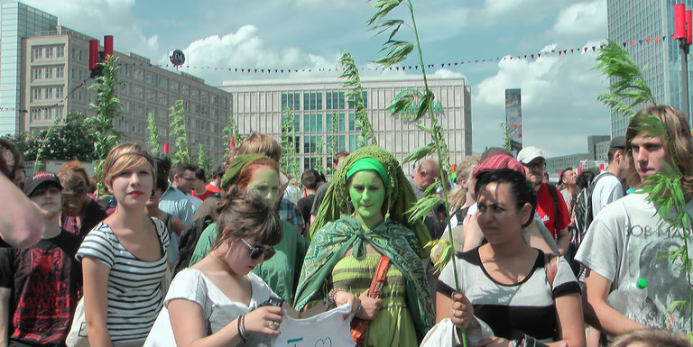 Foto von der Hanfparade 2011 mit bunt geschmckten DemonstrationsteilnehmerInnen und vielen Nutzhanfpflanzen