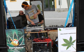 Foto vom DJ am DJ-Pult neben Demoschildern