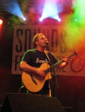 Foto von Götz Widmann mit Gitarre auf einer Bühne