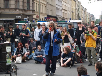 Foto von einem Redner auf dem Heinrichplatz, im Hintergrund Polizeiautos